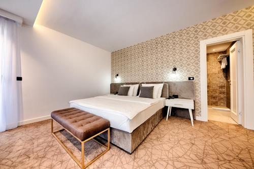 a bedroom with a large bed and a stool at Kalamper Hotel & Spa in Dobra Voda