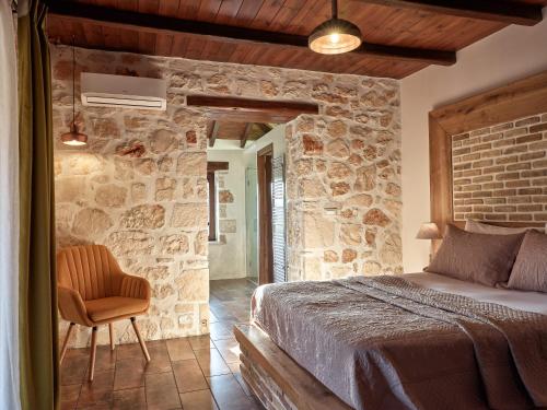 a stone walled bedroom with a bed and a chair at Villa Meralia in Anafonítria