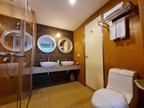 a bathroom with two sinks and two mirrors at Swan Garden Hotel in Melaka