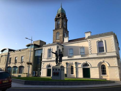 a building with a statue in front of it with a clock tower at Central Lisburn Duplex Apartment No Parties in Lisburn