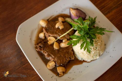 a plate of food with meat and nuts and rice at Pousada Yapara-Tyba in Japaratinga
