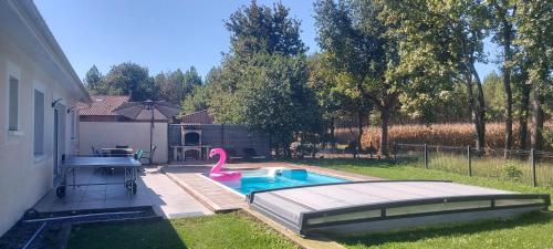 a swimming pool with a pink flamingo in a yard at Maison familiale au calme avec piscine securisee in Le Barp