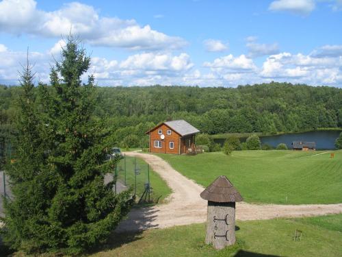 a house in the middle of a field next to a tree at Svajonių Dvaras in Balninkai
