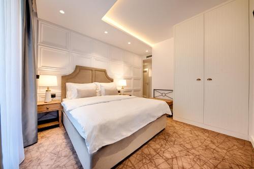 a bedroom with a large white bed and a desk at Kalamper Hotel & Spa in Dobra Voda