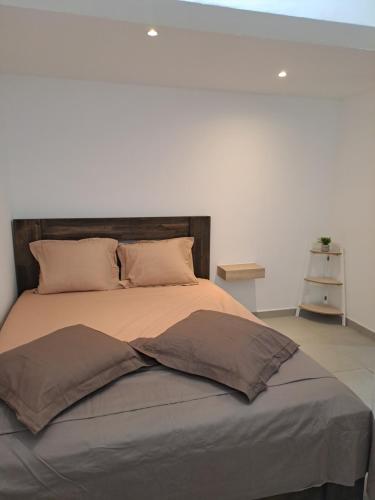 a large bed in a bedroom with a white wall at Appartement Cosy, T2 Situé en Centre ville de Saint-Pierre in Saint-Pierre