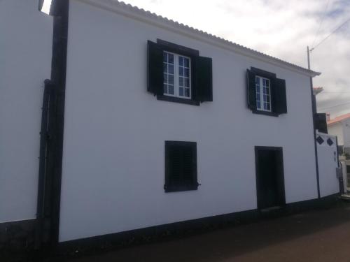 a white building with black windows on a street at Vitamin Sea in São Roque do Pico