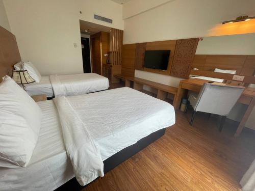 a hotel room with two beds and a desk at Swan Garden Hotel in Melaka