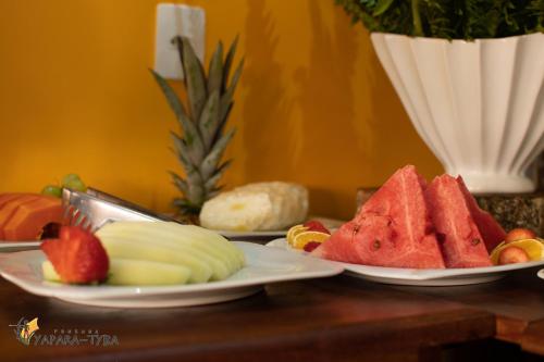 two plates of fruit and vegetables on a table at Pousada Yapara-Tyba in Japaratinga