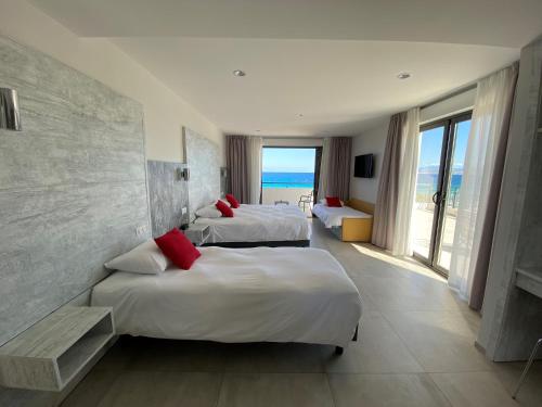 two beds in a room with a view of the ocean at Hôtel L'Isula Marina in LʼÎle-Rousse