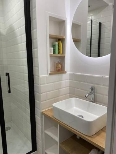 Baño blanco con lavabo y espejo en Super appartement dans le centre de Montmorency en Montmorency