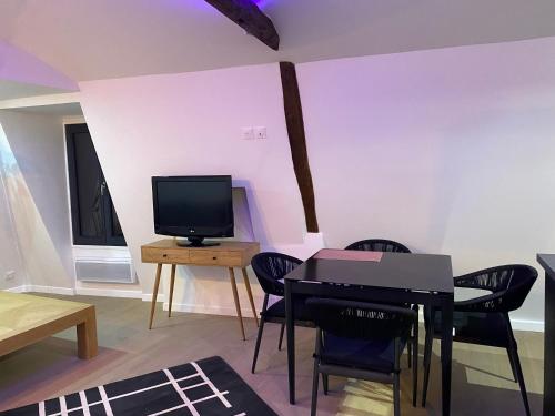 - un salon avec une télévision, une table et des chaises dans l'établissement Super appartement dans le centre de Montmorency, à Montmorency