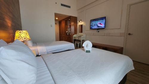 a hotel room with two beds and a flat screen tv at Swan Garden Hotel in Melaka