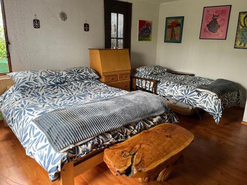 Habitación con 2 camas y mesa de madera. en Loma de las Maravillas, en Curacaví