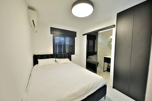 a bedroom with a white bed and a mirror at T'eo 25 suite in Qiryat Yam