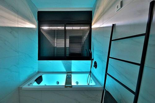 ein Bad mit einer Badewanne und einem Fenster in der Unterkunft T'eo 25 suite in Qiryat Yam