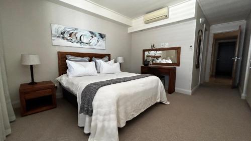 a bedroom with a large white bed and a mirror at Canal Quays 507 in Cape Town