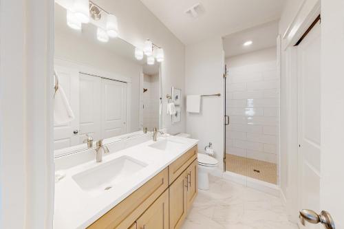 a white bathroom with two sinks and a toilet at 51 Magical Place in Santa Rosa Beach