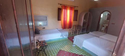a room with two beds and a mirror at Maison Vallée Du Ziz in Ouled Aissa