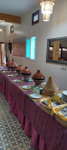 a long table with plates and bowls on top of it at Maison Vallée Du Ziz in Ouled Aissa