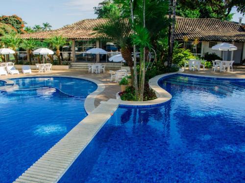 a resort swimming pool with a palm tree in the middle at Hotel Recanto da Cachoeira in Socorro