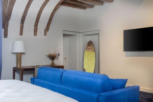 un salon avec un canapé bleu et une télévision dans l'établissement La Borde en Sologne Château & Spa, à Vernou-en-Sologne