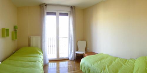 a bedroom with two beds and a large window at Apartamentos Eneriz in Enériz