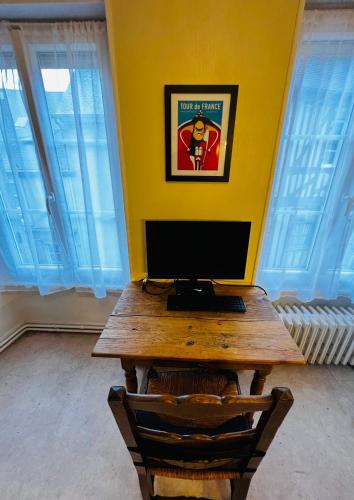 a desk with a computer on top of a yellow wall at A La Maison - hébergement de luxe in Domfront