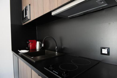 a kitchen with a sink and a black counter top at Kalypso Suites Hotel - Adults Only in Elounda