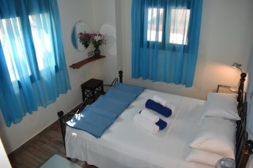 a bedroom with a white bed with blue curtains at Anemos-Halcyon-Eirene in Mochlos
