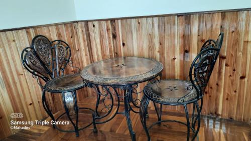 a table and two chairs in front of a wooden wall at The Brick House Stay in Kalimpong