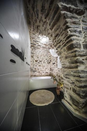 a bathroom with a stone wall and a bath tub at Vilitsa Holiday House in Pyrgi