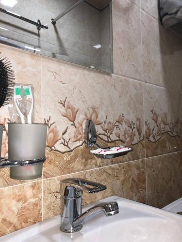 a bathroom sink with a toothbrush in a pot on the wall at Hotel Mohina in Samarkand