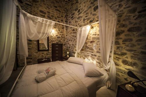 Un dormitorio con una cama blanca en una habitación con paredes de piedra. en Vilitsa Holiday House en Pyrgi