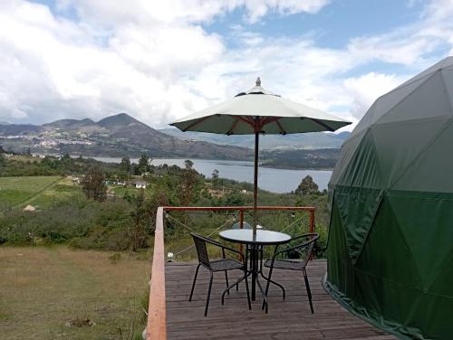 a table and chairs on a deck with an umbrella at Glamping El Refugio in Guatavita