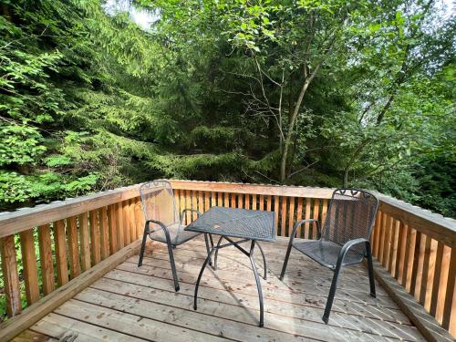 two chairs and a table on a wooden deck at Apartmány NONE in Branná