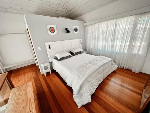 Schlafzimmer mit einem großen weißen Bett und Holzböden in der Unterkunft Punta Ballena Punta del Este in Punta del Este