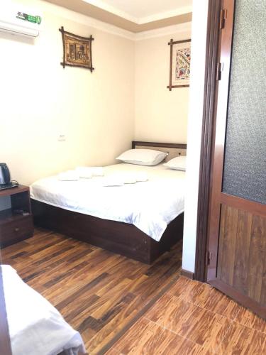 a bedroom with a bed and a wooden floor at Hotel Mohina in Samarkand
