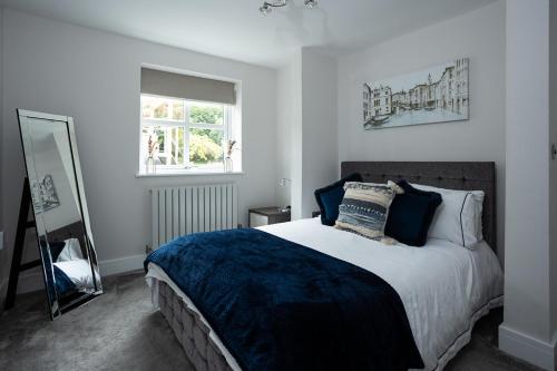 a bedroom with a bed with a blue blanket and a mirror at Quiet Luxury Countryside 2 Bedroom Detached Home in Shudy Camps