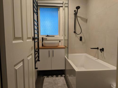 baño con lavabo, bañera y ventana en Peaceful country home in a middle of a rainforest, en Cockatoo