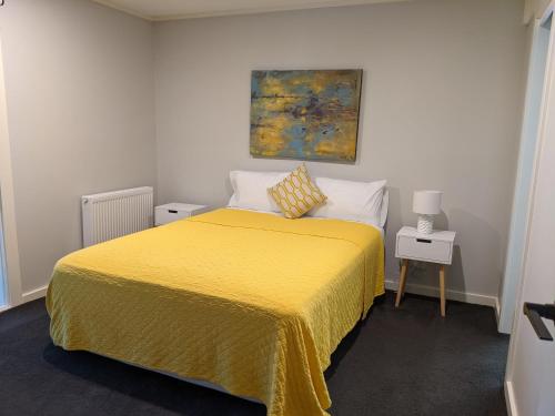 Un dormitorio con una cama amarilla y una pintura en la pared en Peaceful country home in a middle of a rainforest, en Cockatoo