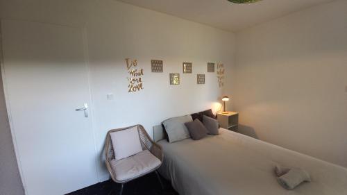 - une chambre avec un grand lit blanc et une chaise dans l'établissement Adorable studio avec entrée indépendante, à Dijon