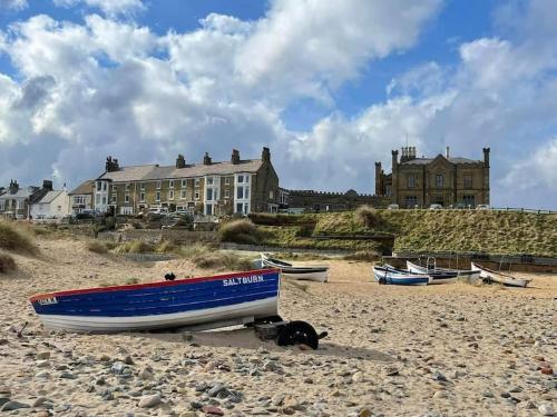 un barco azul sentado en la arena en una playa en Sandstone Cottage en Marske-by-the-Sea