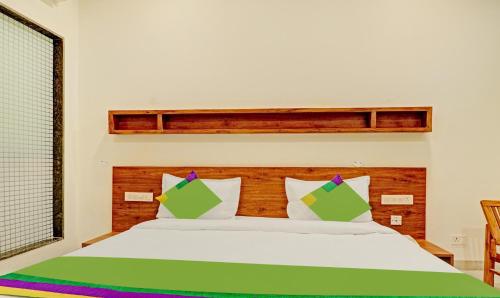 a bed with green and white pillows in a room at Treebo Delmont in Chandīgarh