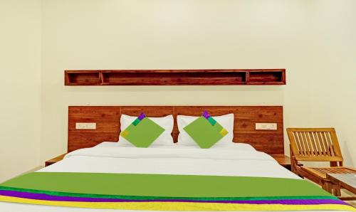 a bed with green and white sheets and a wooden headboard at Treebo Delmont in Chandīgarh