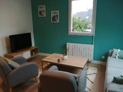 sala de estar con sofá, mesa y TV en Appartement Zen au Cœur du Cotentin, en Valognes
