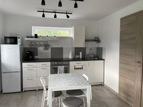 a white kitchen with a table and a white refrigerator at Panoramic tranquility on hill of vineyard in Csopak