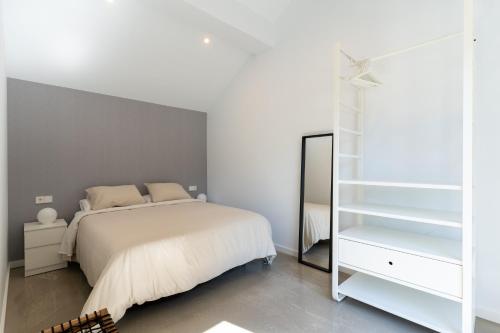 a bedroom with a white bed and a mirror at NaturBatán in Pontevedra