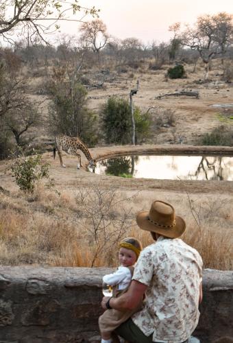 a man holding a baby looking at a giraffe at MILIMA Big 5 Safari Lodge in Hoedspruit