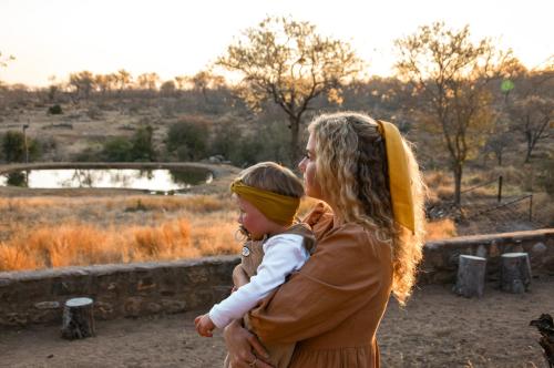 a woman holding a child in her arms at MILIMA Big 5 Safari Lodge in Hoedspruit