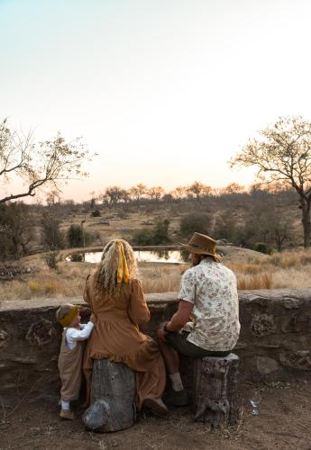 a group of three women and a child sitting on a wall at MILIMA Big 5 Safari Lodge in Hoedspruit